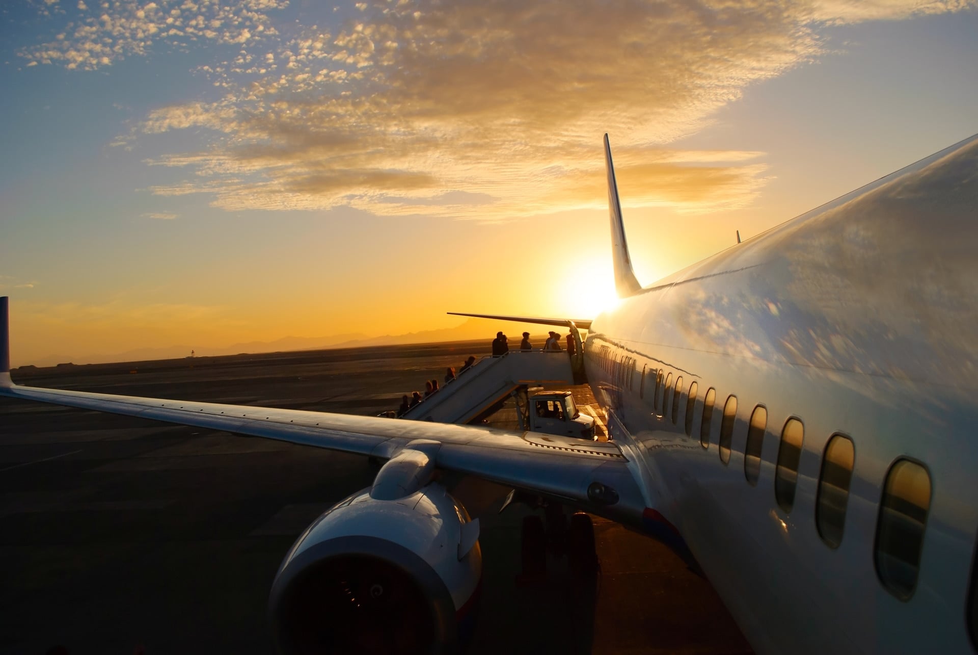 View over the wing of a charter aircraft crossing Asian airspace at sunset