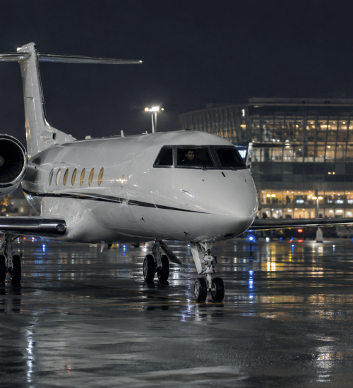 Ground handling marshaller guiding a private jet on a night arrival